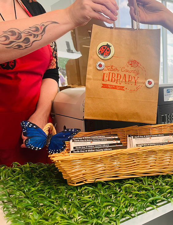 Librarain giving a paper bag of lady bugs to a patron